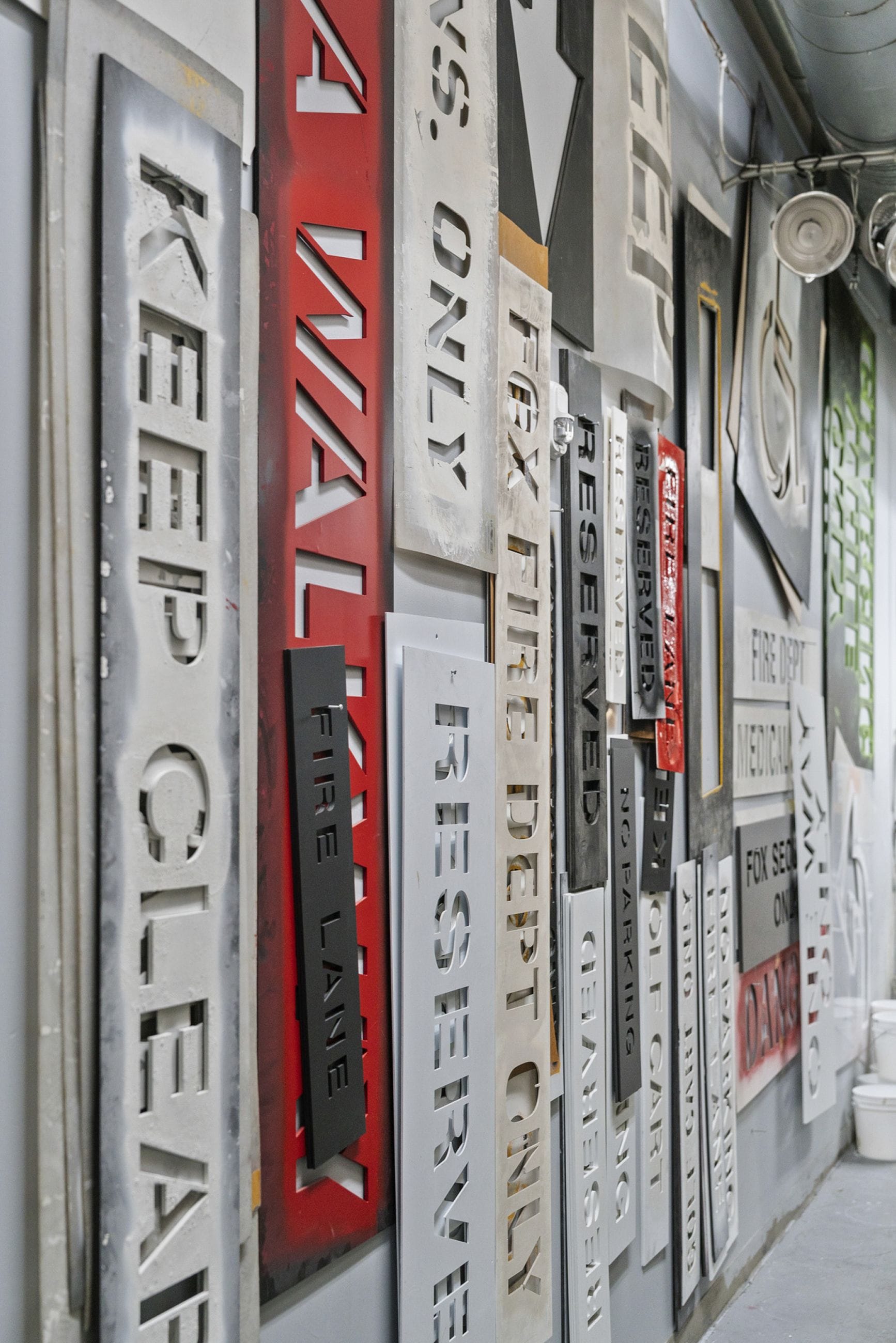 A wall covered with various stenciled metal signs, including "KEEP CLEAR," "FIRE LANE," and "RESERVED."