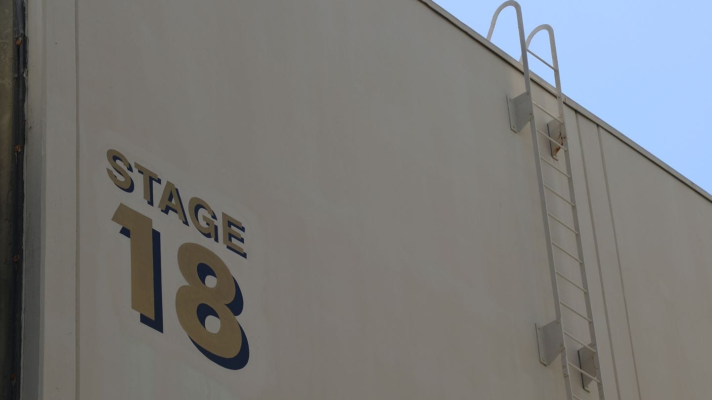 Side of a building with "STAGE 18" and a white industrial ladder.