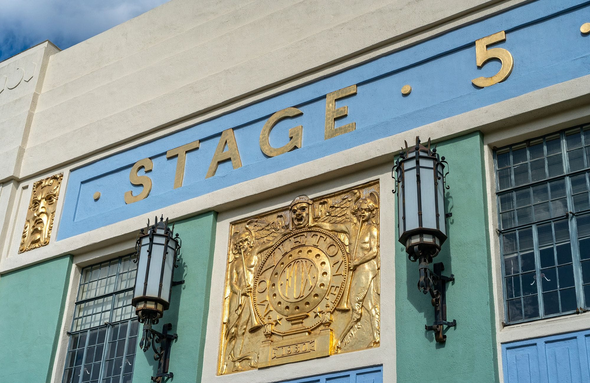 Art Deco building facade with "STAGE 5" in gold letters and ornate gold relief panels.