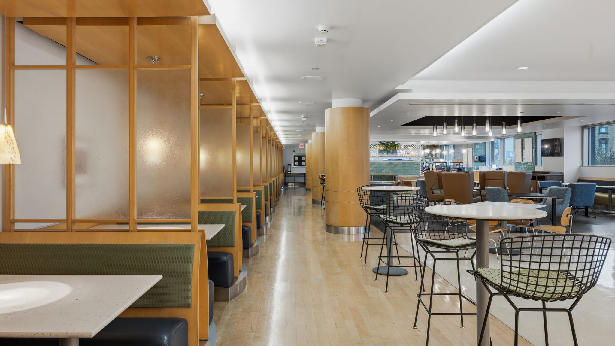Modern cafeteria with a row of booths, high-top tables, and lounge seating.
