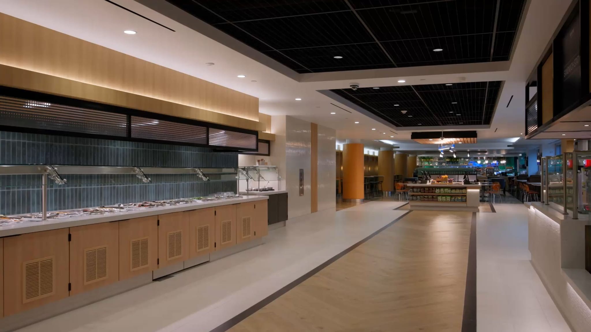A clean, modern cafeteria with an empty buffet line and spacious seating area.