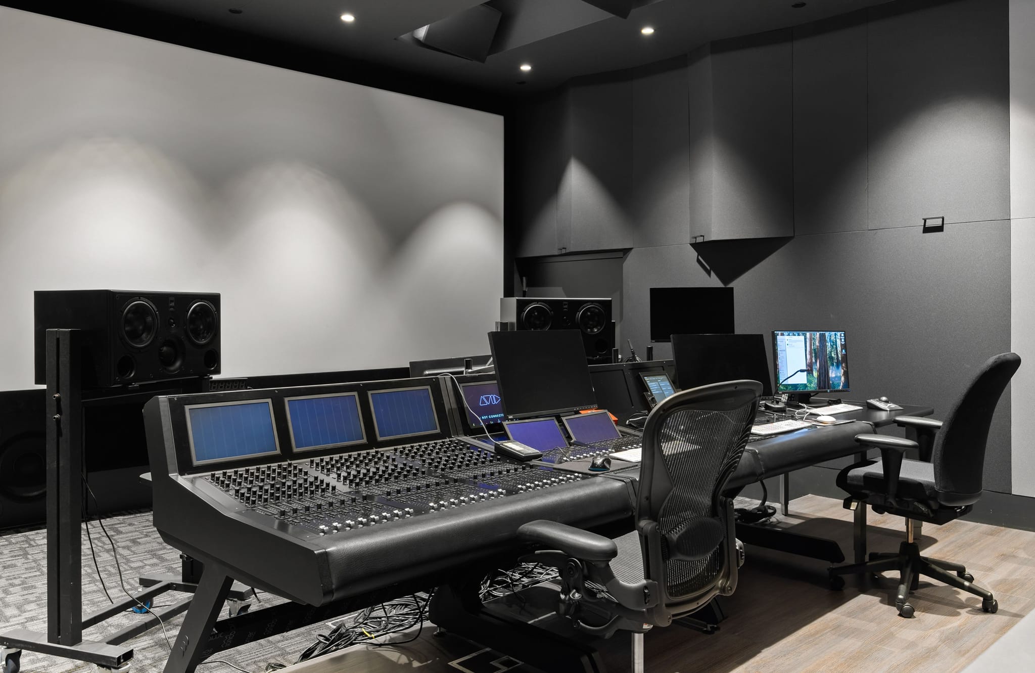 Darkened media room with a large screen and a long table equipped with computers.