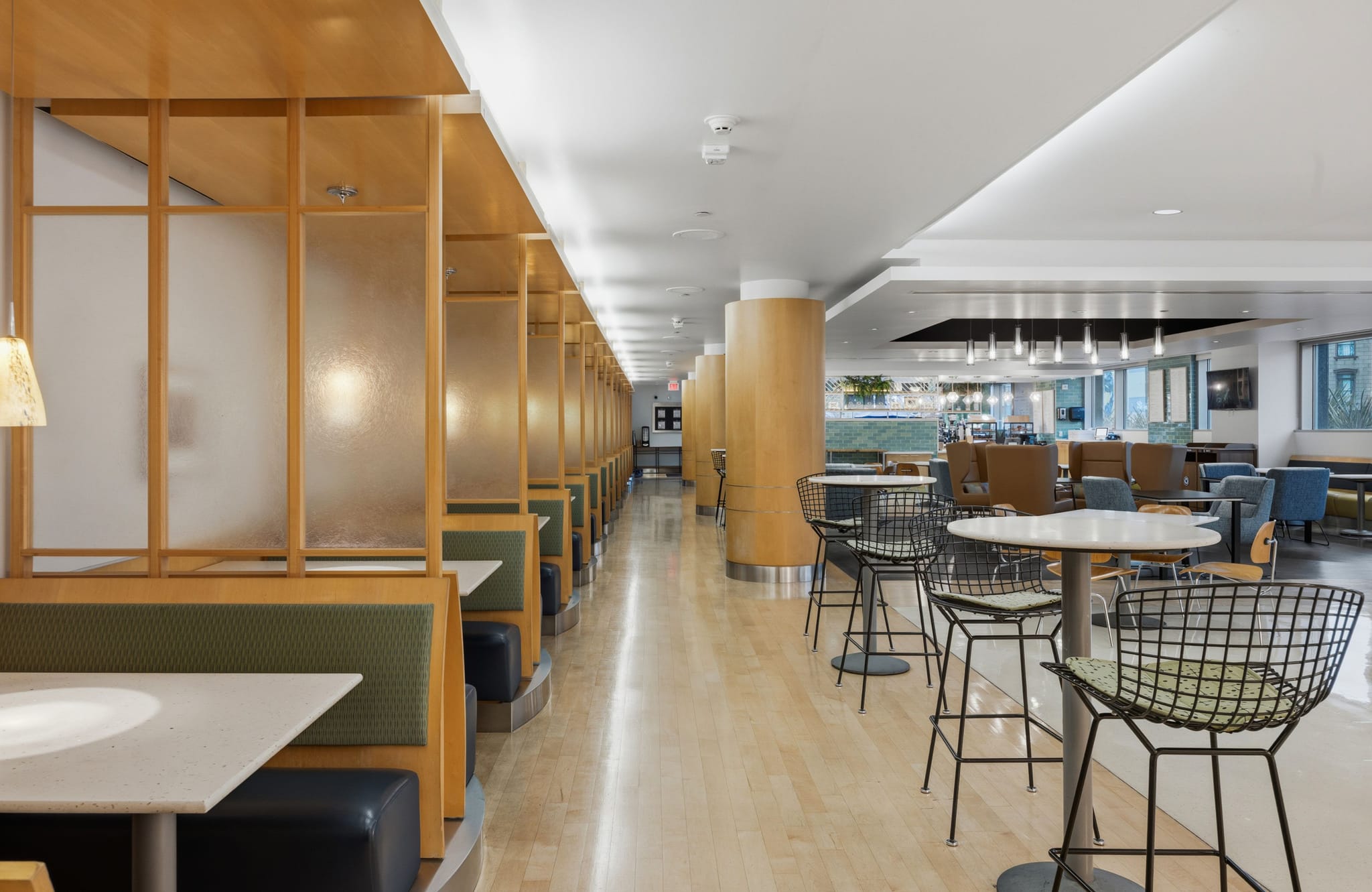 Empty modern cafeteria featuring booth seating, high-top tables, and a lounge area.