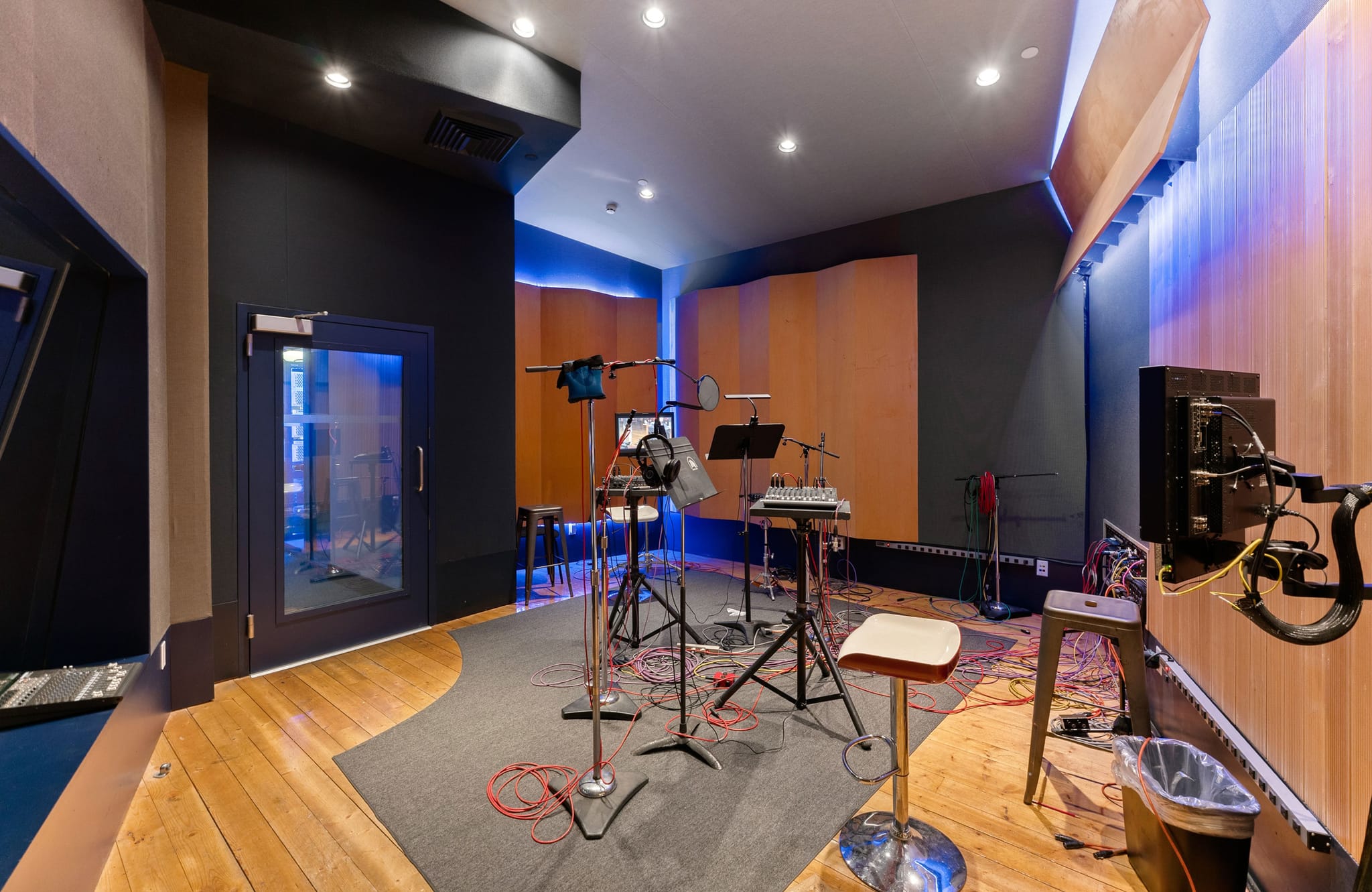 A modern recording studio with microphones, soundproofing panels, and blue accent lighting.