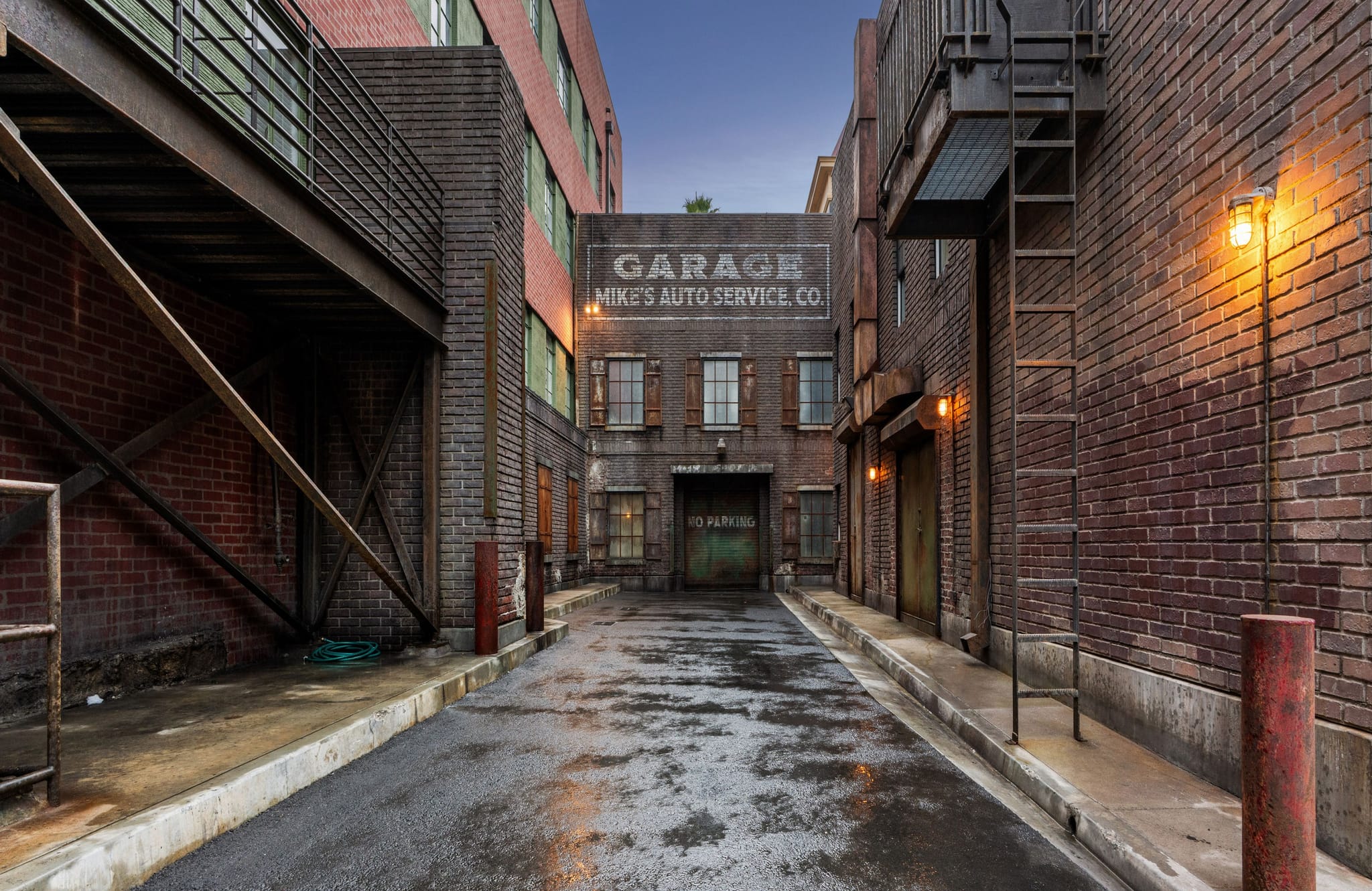 A wet alleyway between brick buildings leading to a garage signed "Mike's Auto Service Co.".