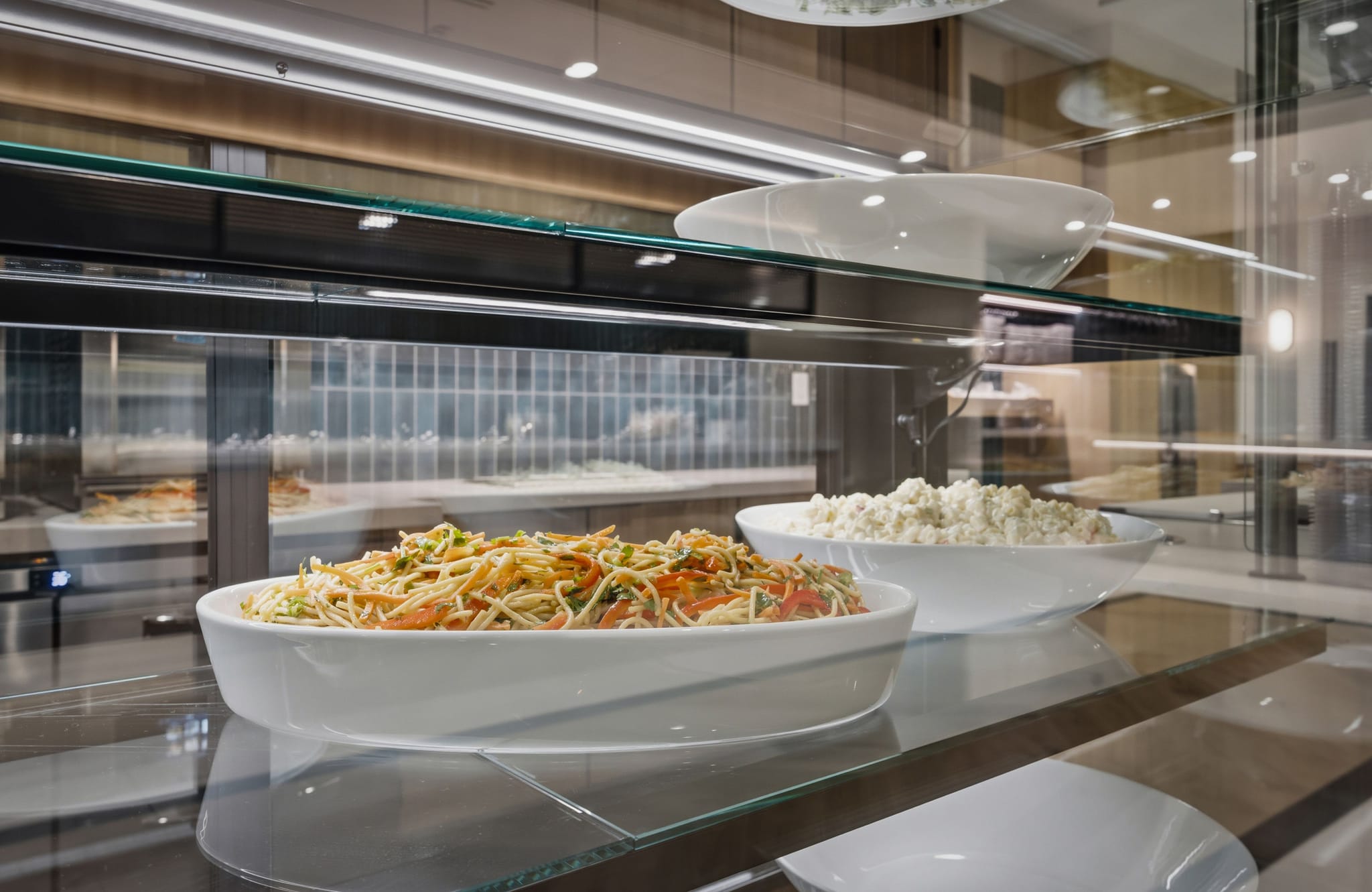 Noodle dish and cottage cheese in a cafeteria display case.