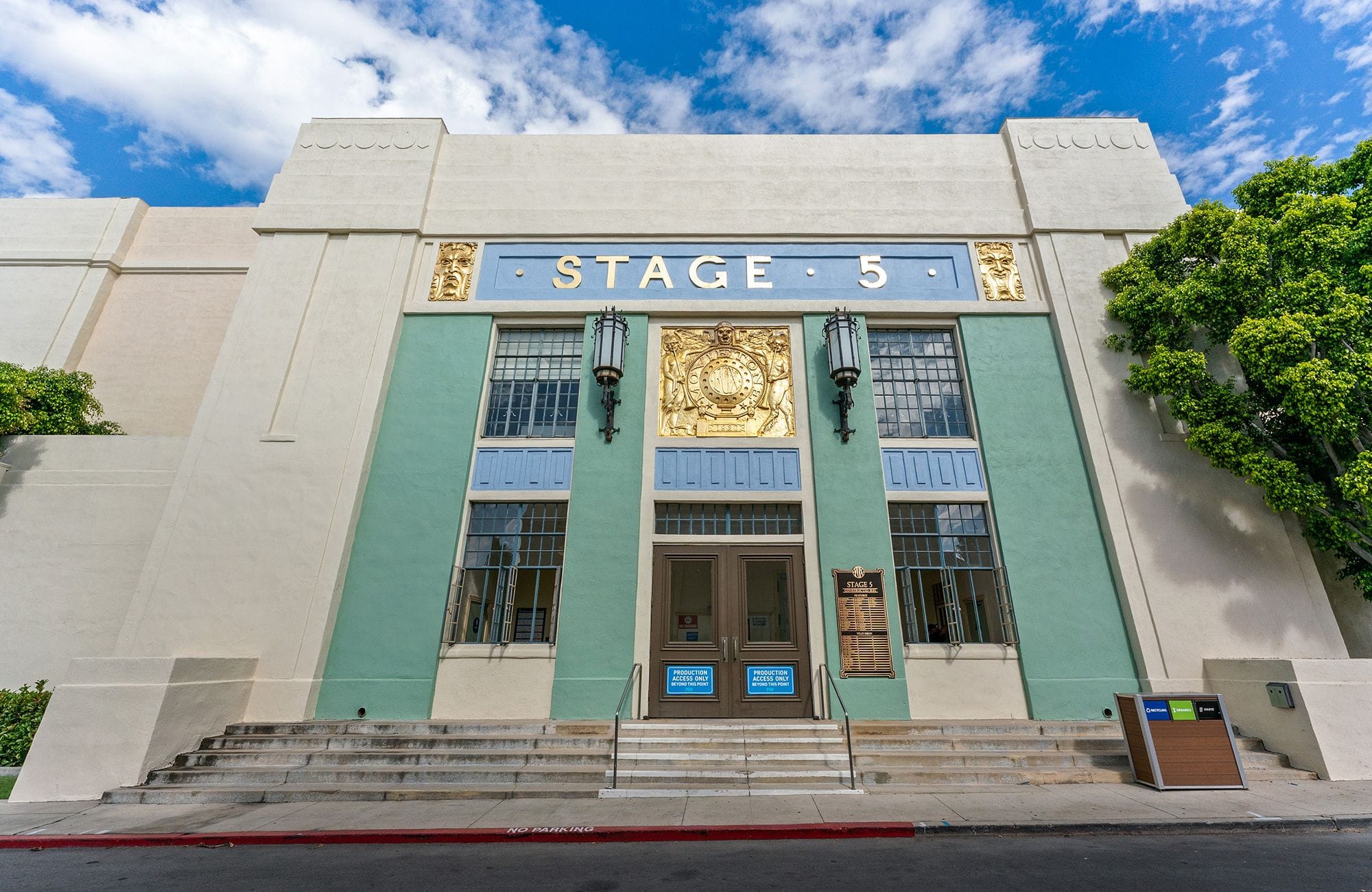 Art Deco "STAGE 5" building facade in teal, cream, and gold with a wide staircase.