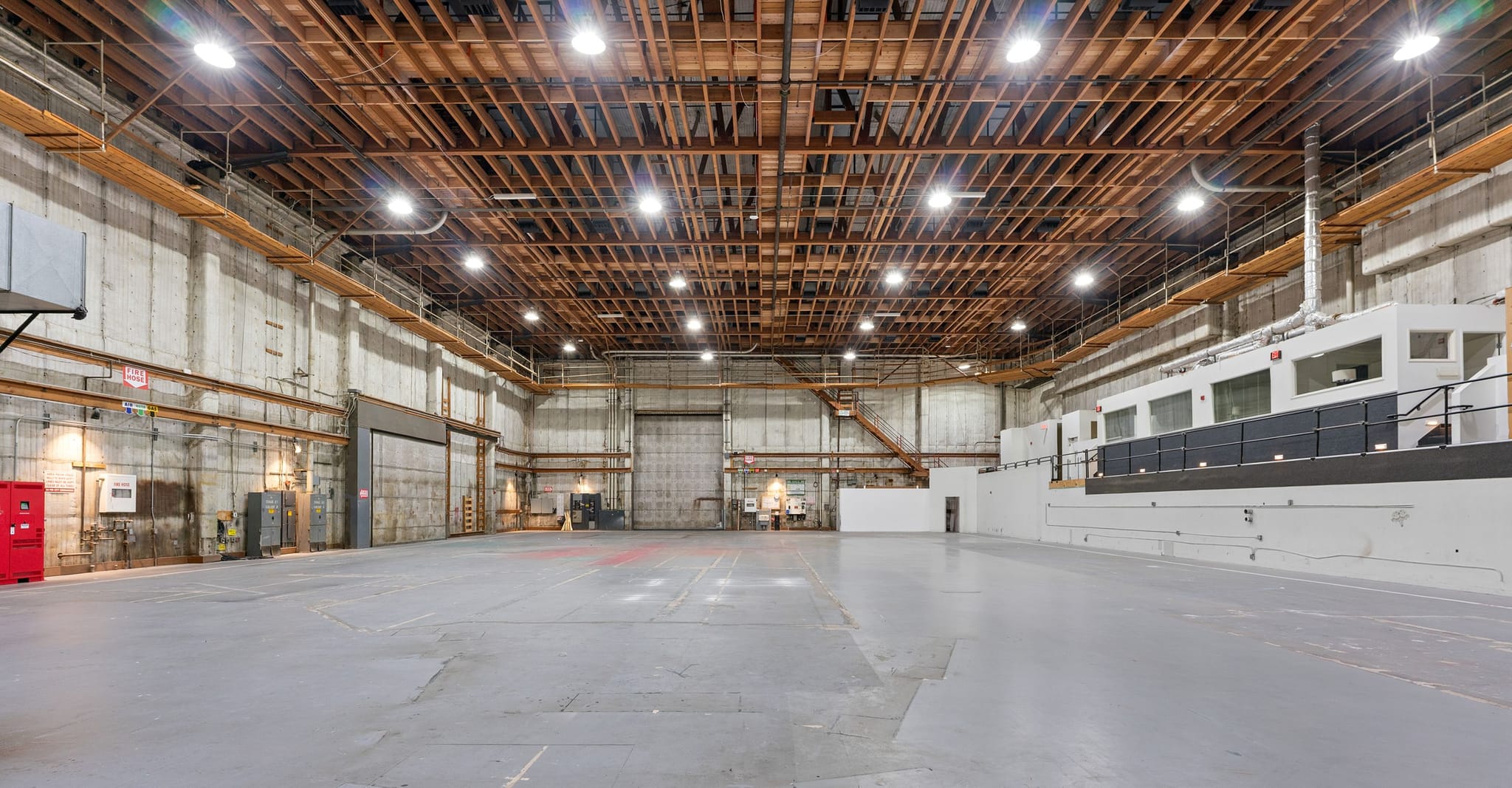 A large, empty industrial warehouse with a high wooden beam ceiling and an integrated office structure.
