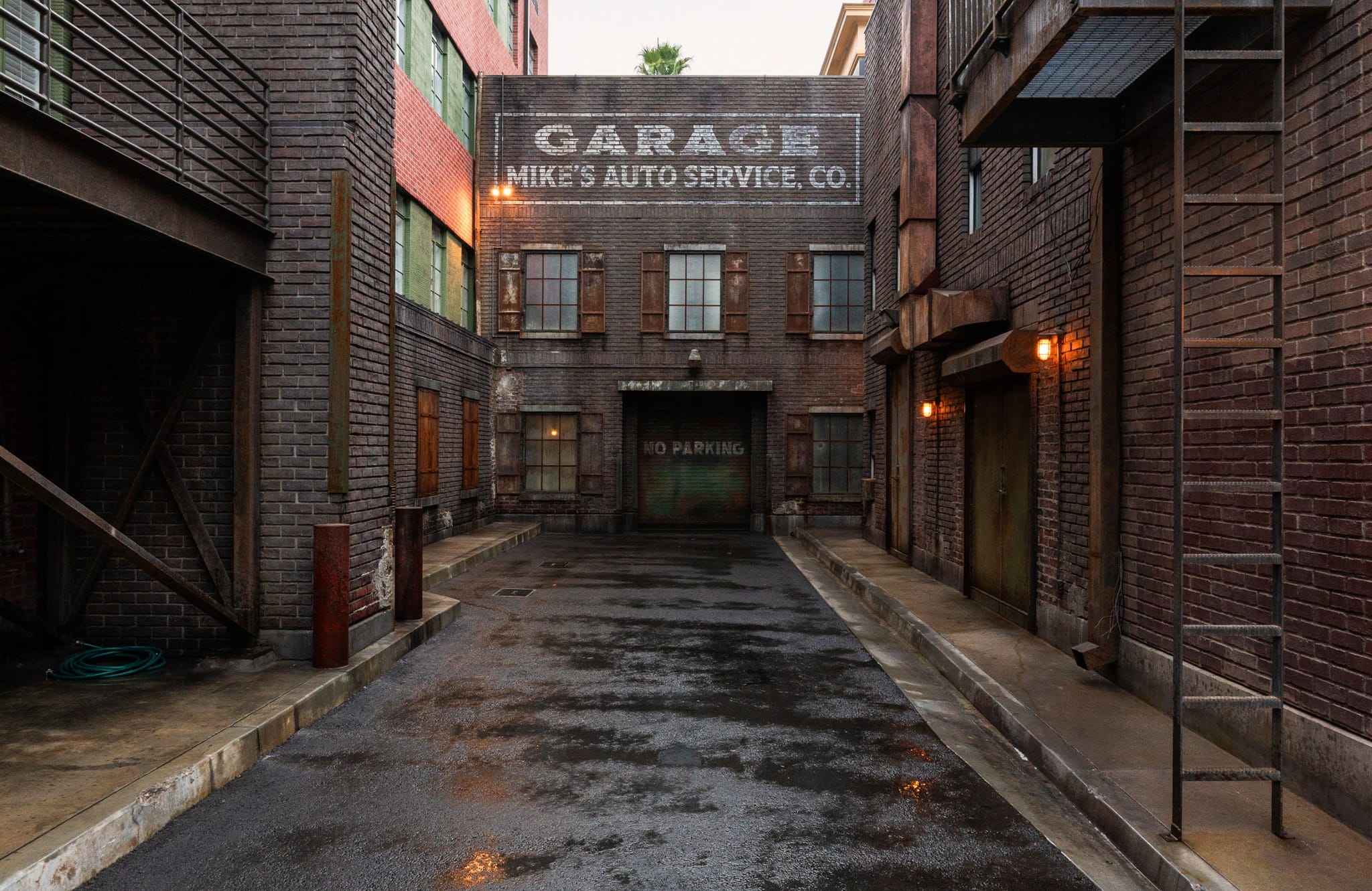 A wet, dark alleyway between brick buildings, with a "Mike's Auto Service" sign on a garage at the end.