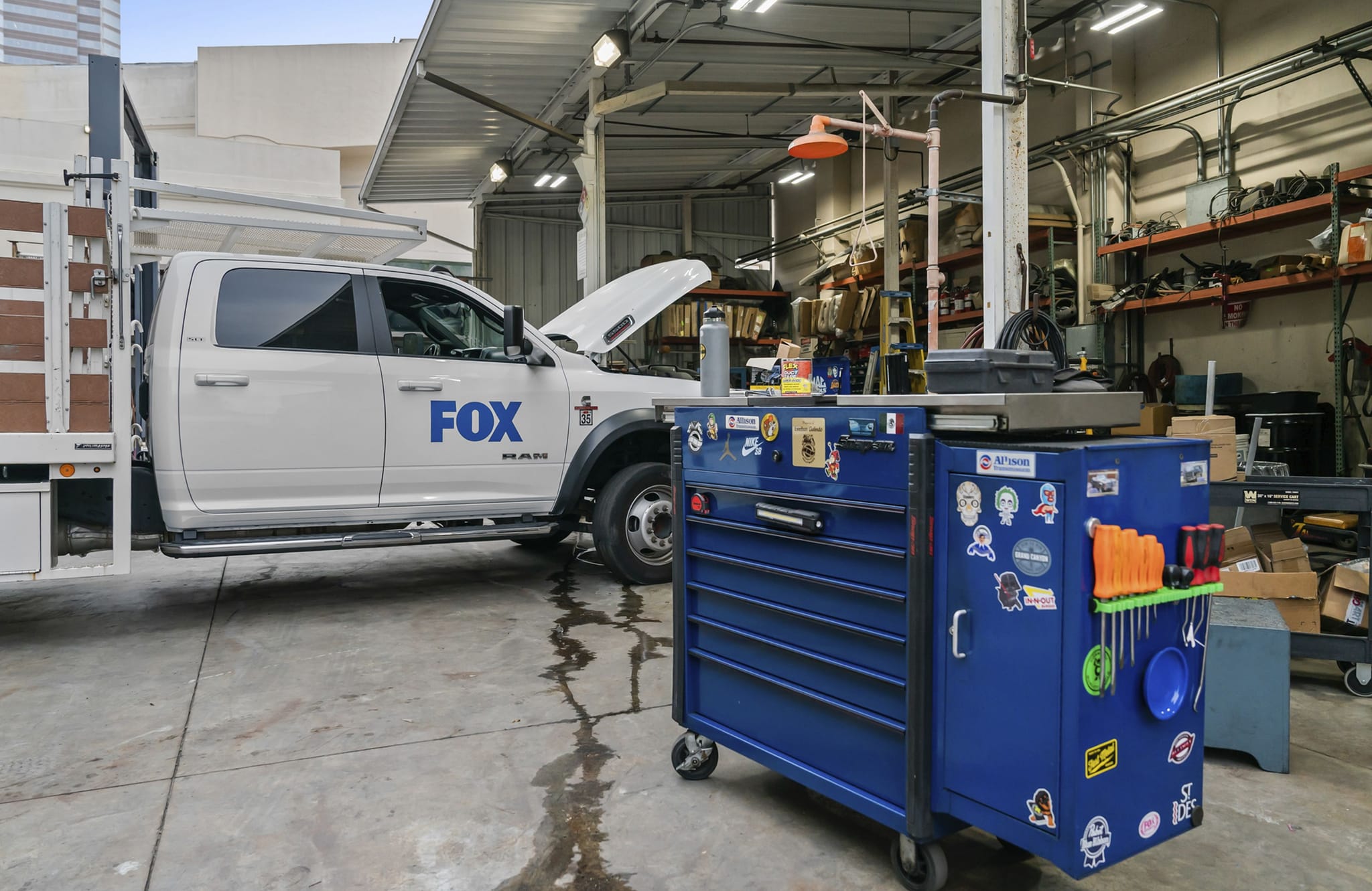 A white Fox Ram truck with its hood open in a garage, next to a blue toolbox.