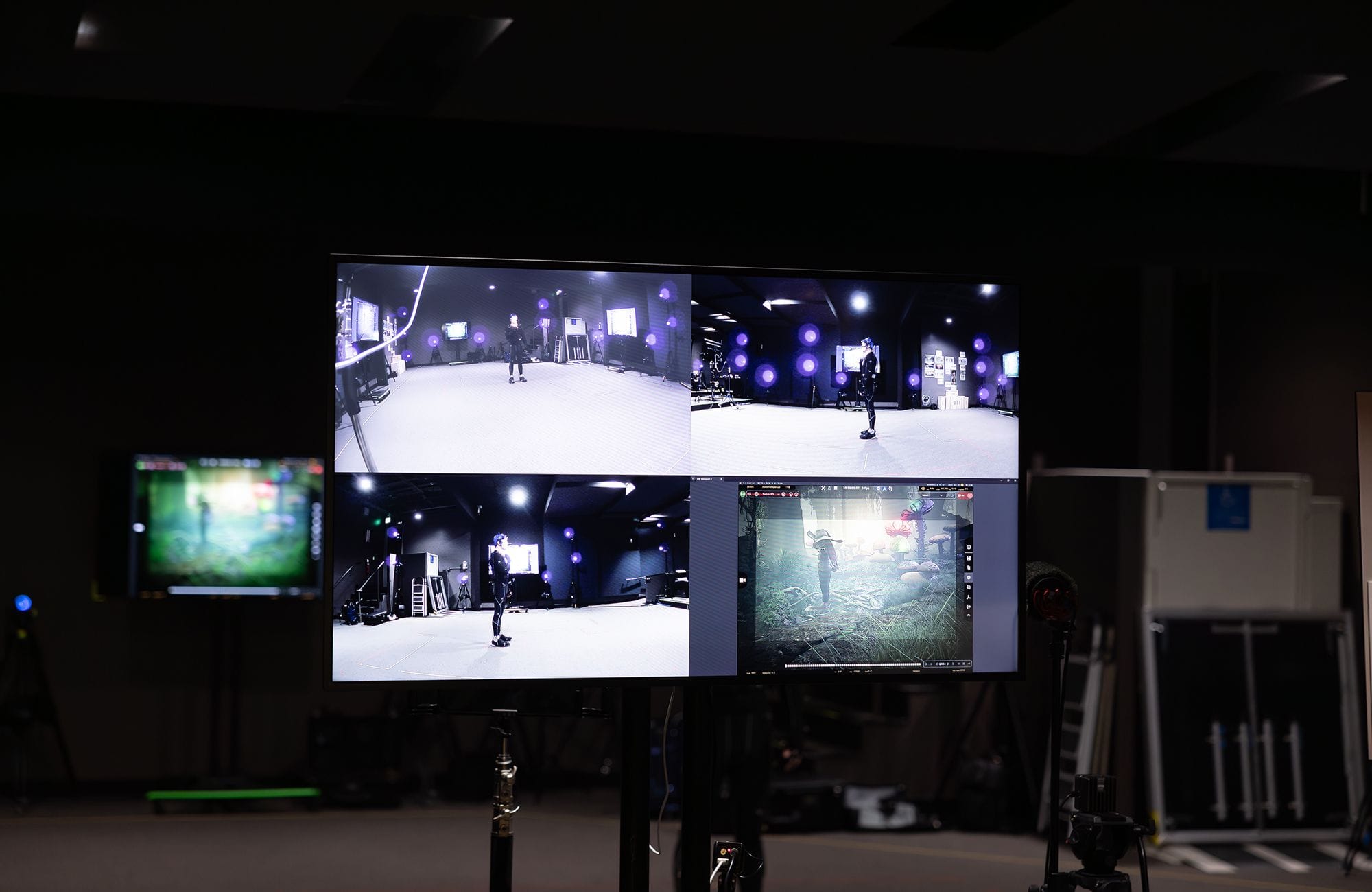 Multi-screen display in a motion capture studio showing a performer and their virtual character.