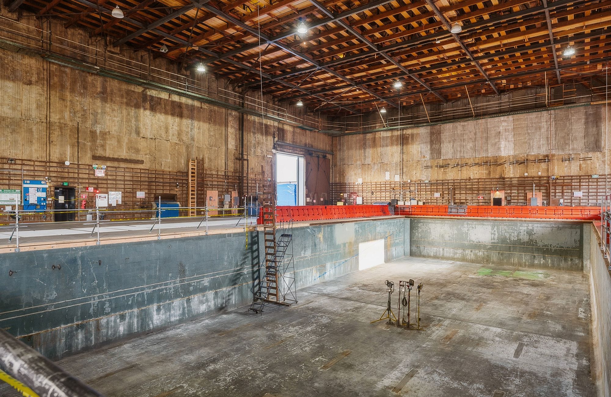 A large, empty indoor dry dock with concrete walls and a wooden ceiling.