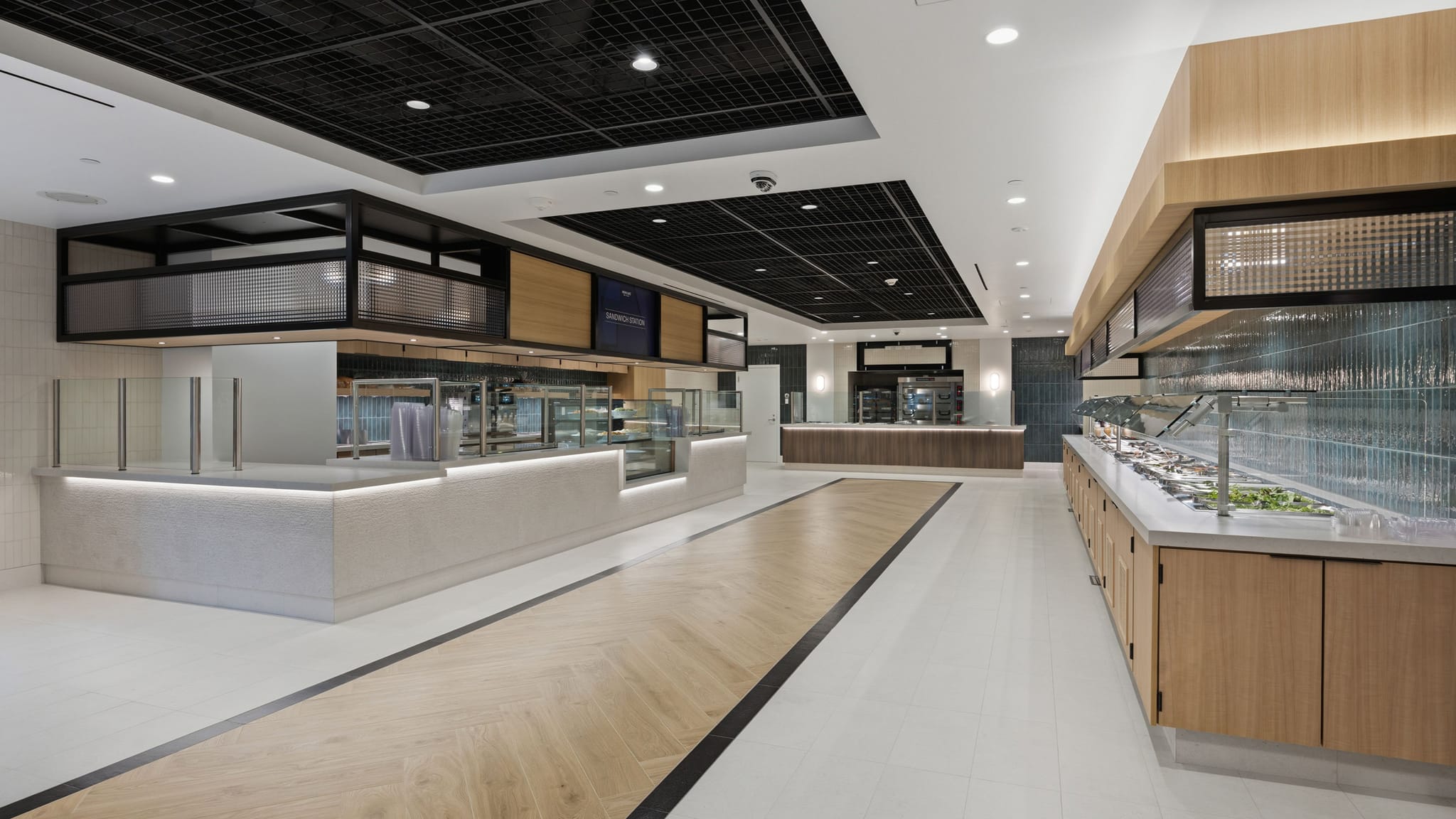 Modern and empty cafeteria with multiple sleek serving counters and a long salad bar.