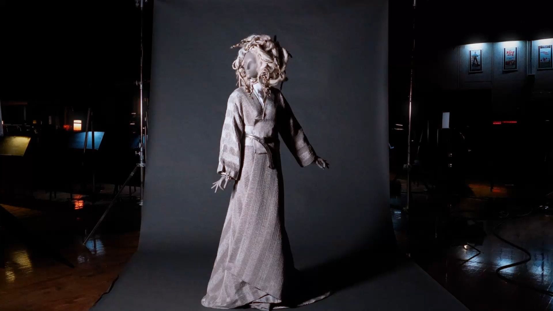Mannequin in a grey textured robe and elaborate light-colored tangled headpiece on a studio backdrop.