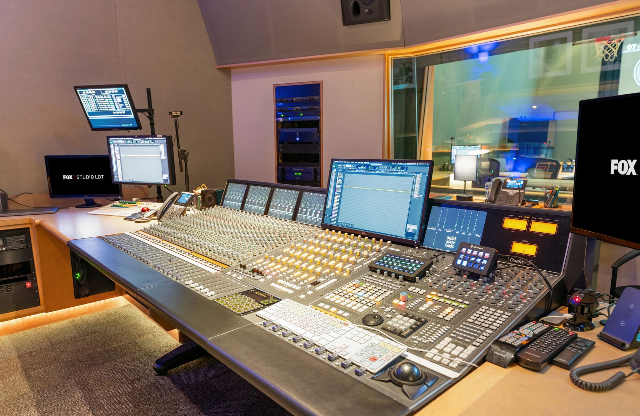 Professional audio mixing studio with a large console and multiple screens, one displaying the FOX logo.