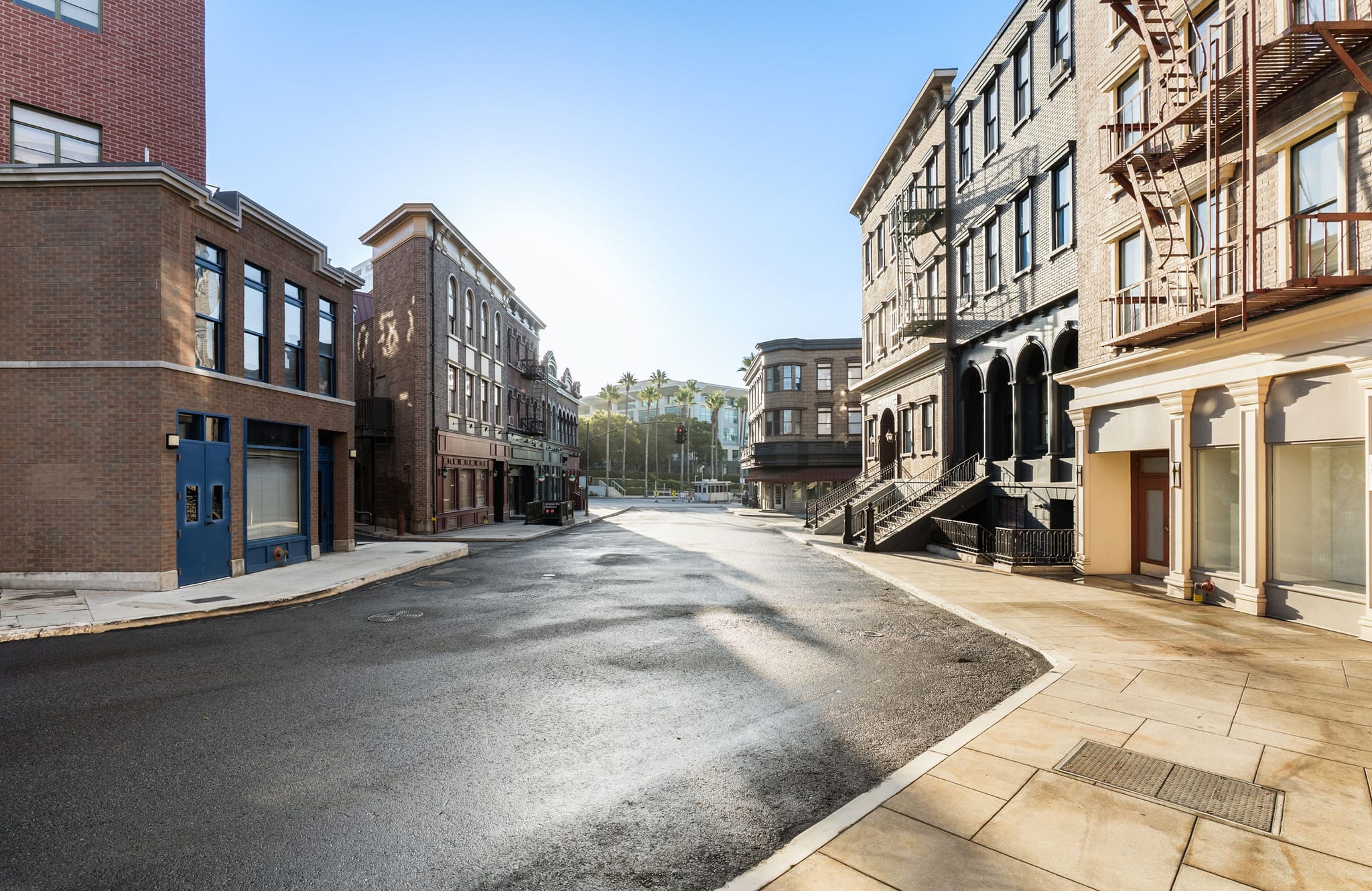 An empty street lined with various buildings under a bright, clear sky.