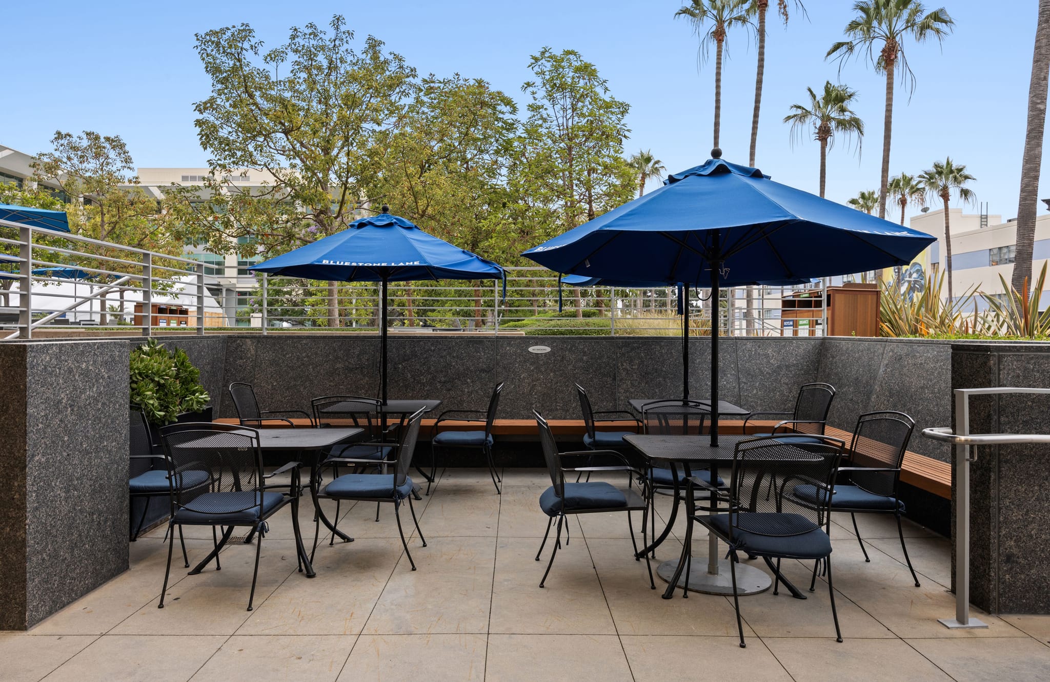 Outdoor patio with tables, chairs, and blue umbrellas.
