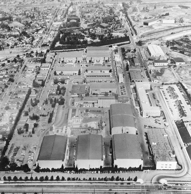 Aerial black and white photo of a large studio complex featuring multiple sound stages, surrounded by urban development.