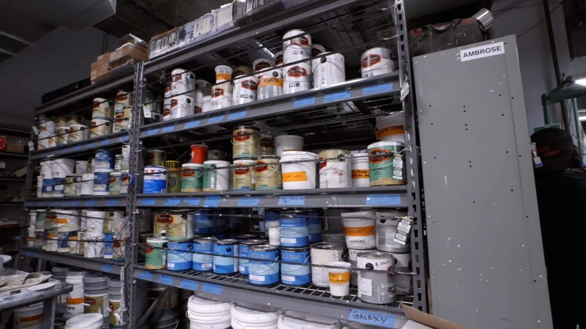 Rows of paint cans and buckets on industrial metal shelves.