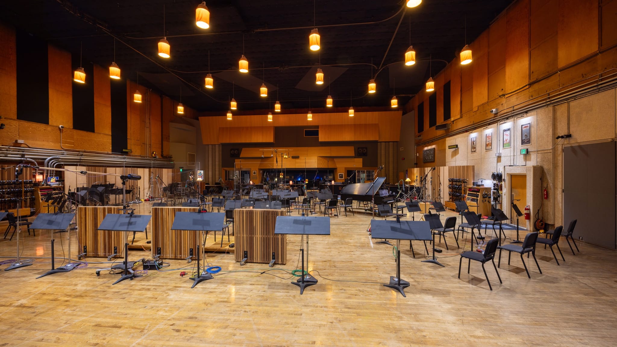 A spacious recording studio with music stands, chairs, and a grand piano.