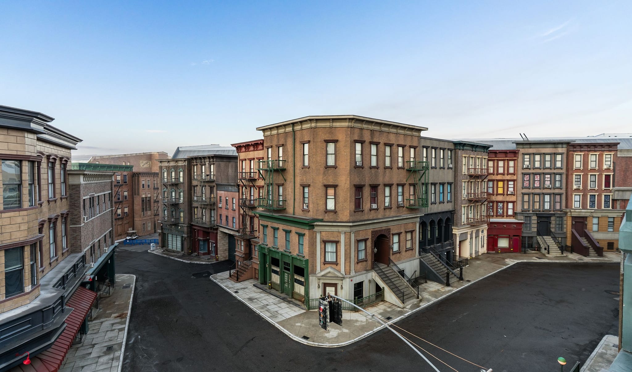 A deserted city street corner lined with multi-story buildings, many featuring fire escapes.