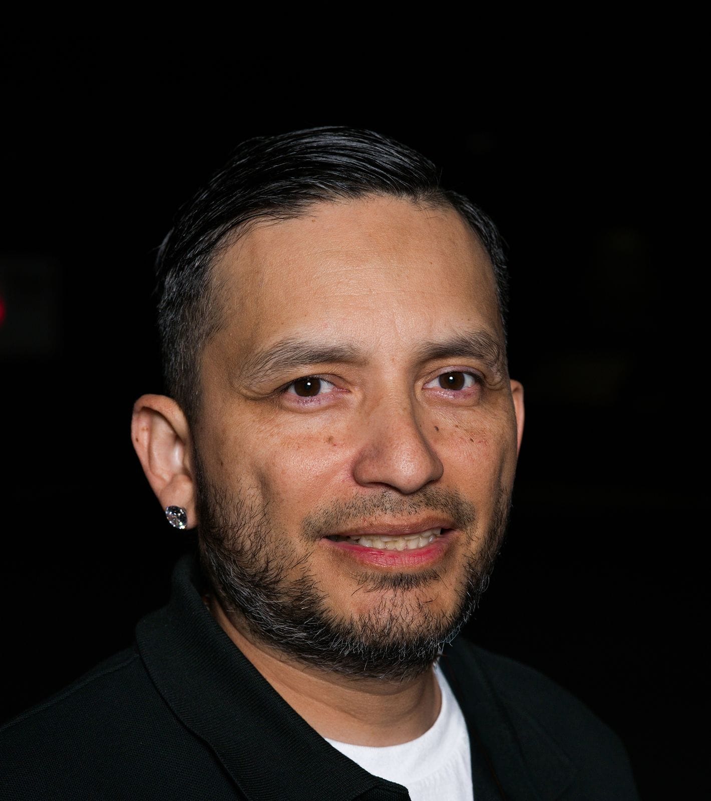 Smiling man with dark hair, a beard, and an earring.