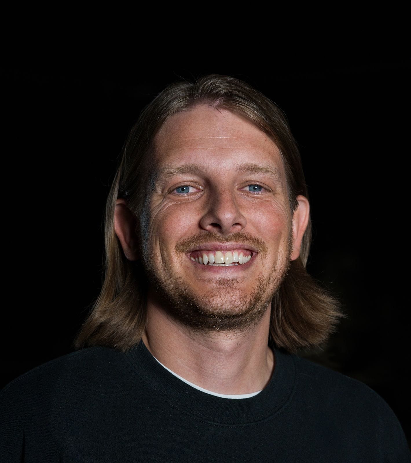 Smiling man with long blonde hair, blue eyes, and a beard.