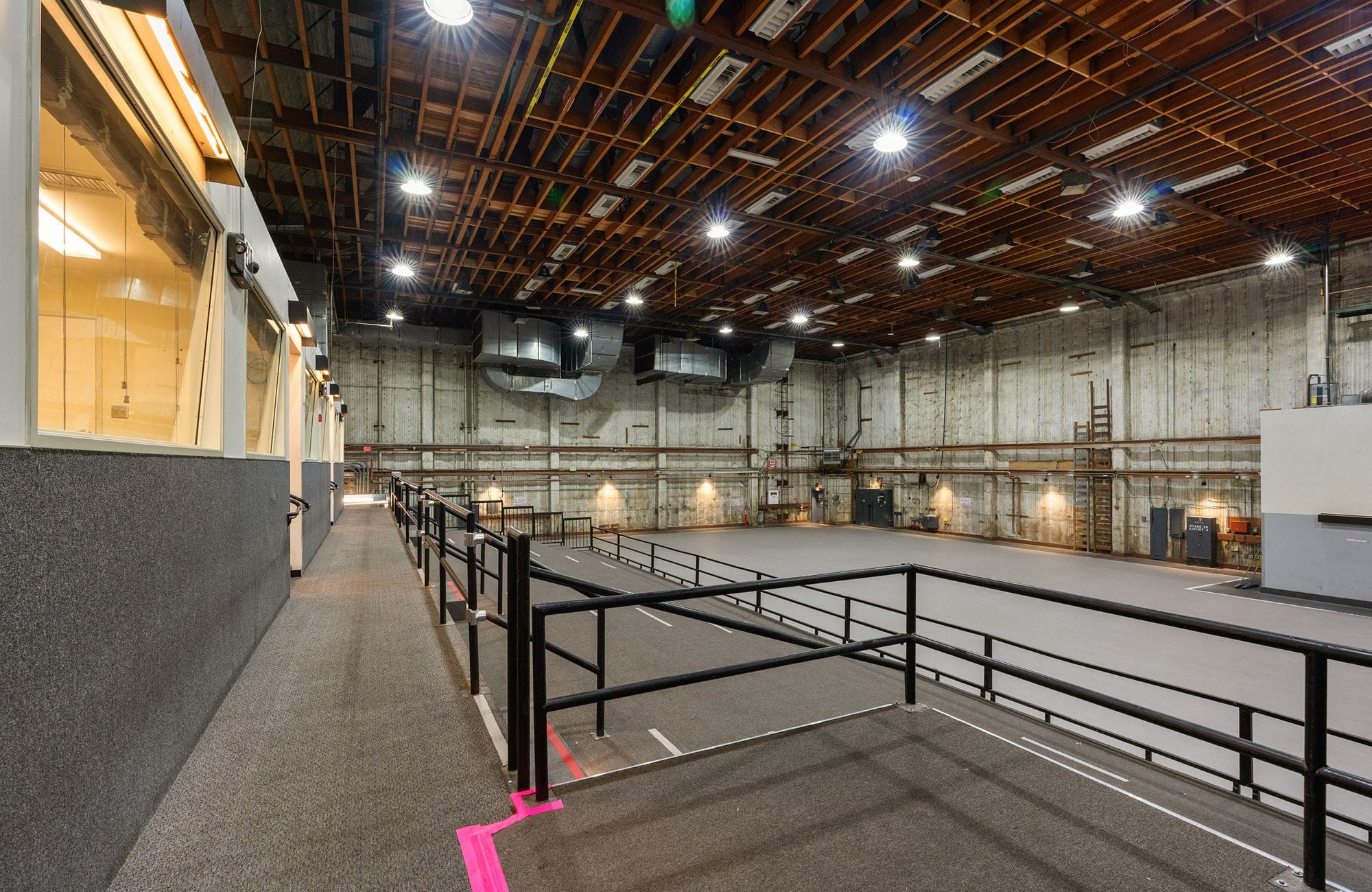 A brightly lit, empty soundstage with a raised viewing platform on the left and exposed wooden beam ceiling.