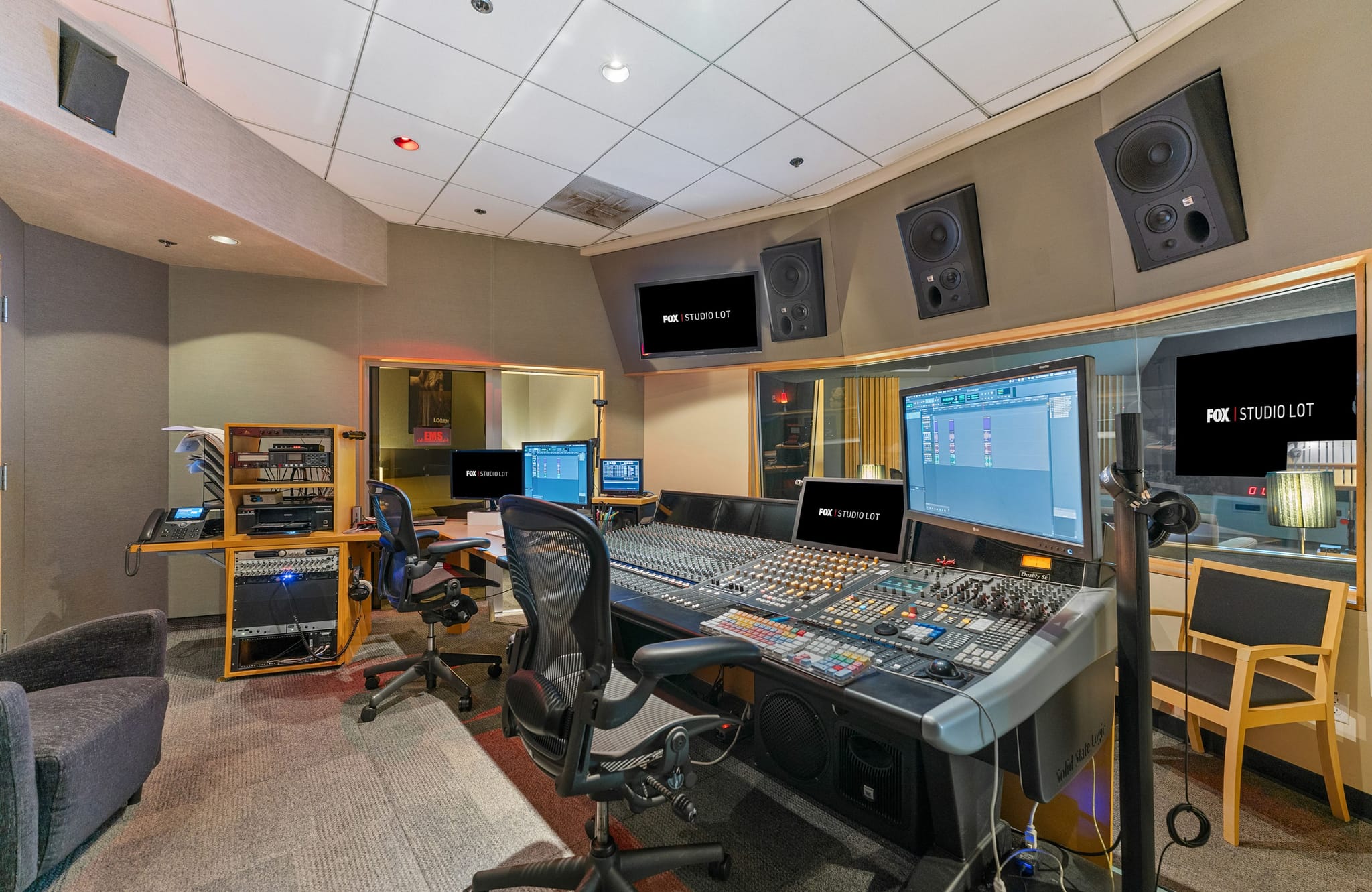 Professional audio recording studio control room with a large mixing console and monitors displaying the FOX | STUDIO LOT logo.