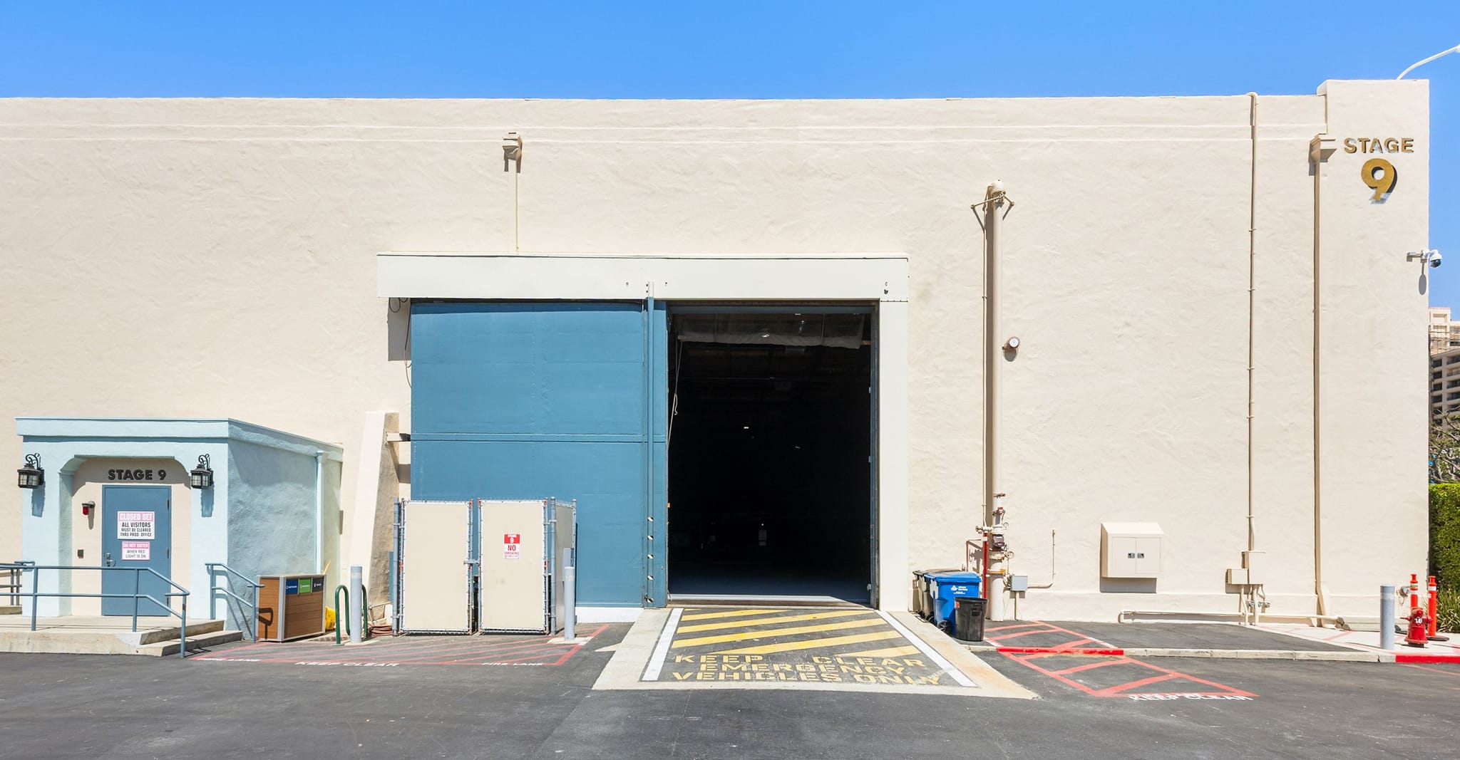 Exterior of a film studio building, Stage 9, with a large, partially open blue loading door.