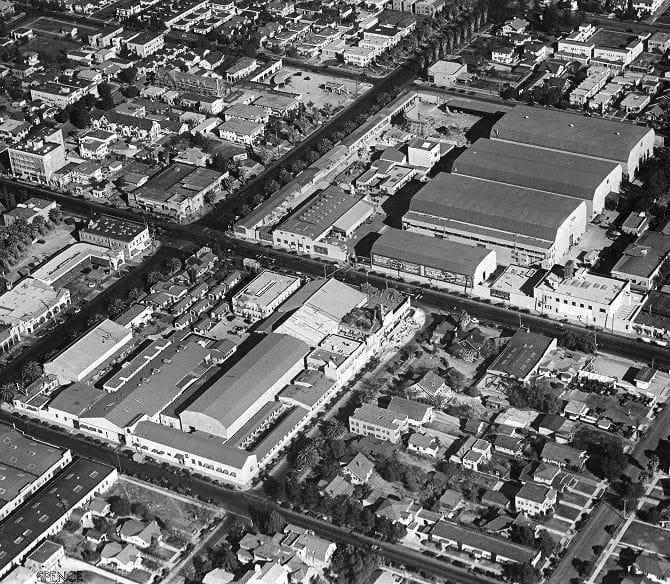 Black and white aerial view of a city featuring large studio buildings, residential homes, and commercial structures.