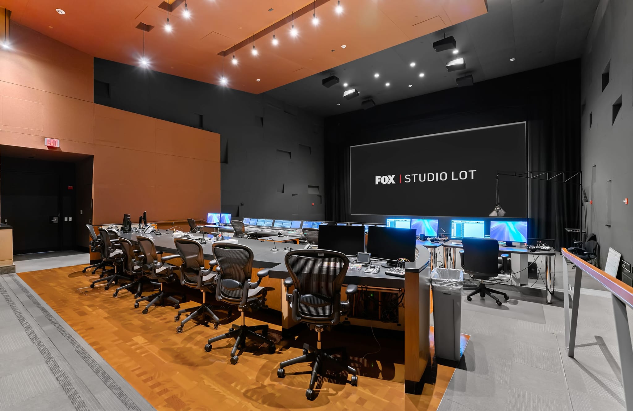 A large media control room with multiple workstations and a screen displaying "FOX | STUDIO LOT".