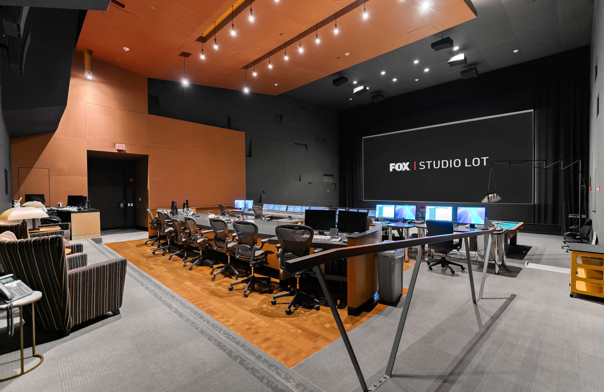 A modern studio control room with multiple workstations facing a large screen displaying "FOX | STUDIO LOT".