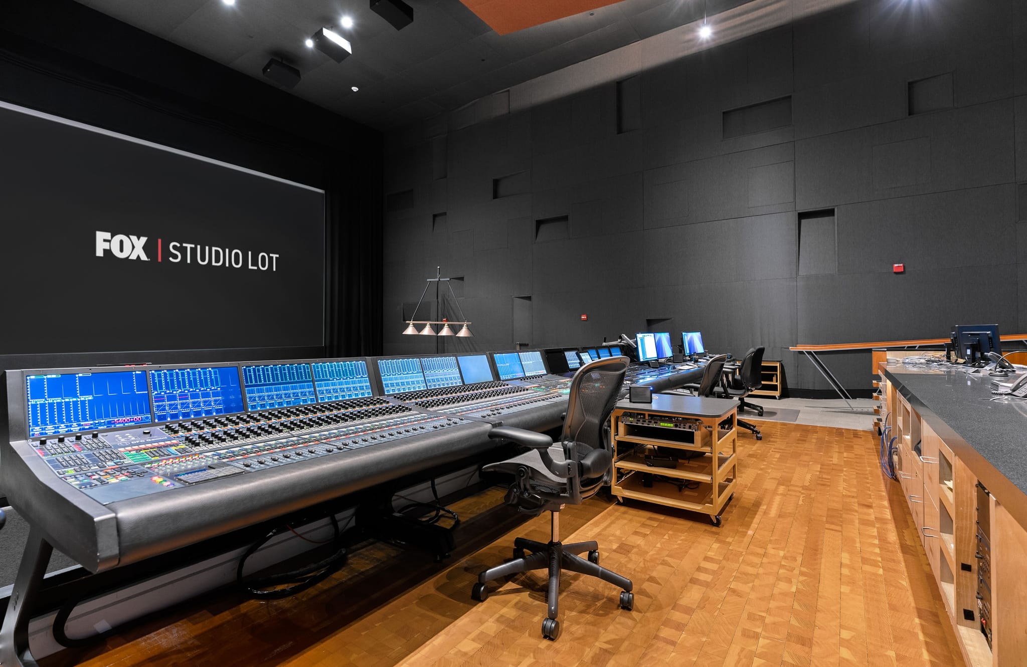 A large studio control room with a massive mixing console and a screen displaying "FOX | STUDIO LOT".