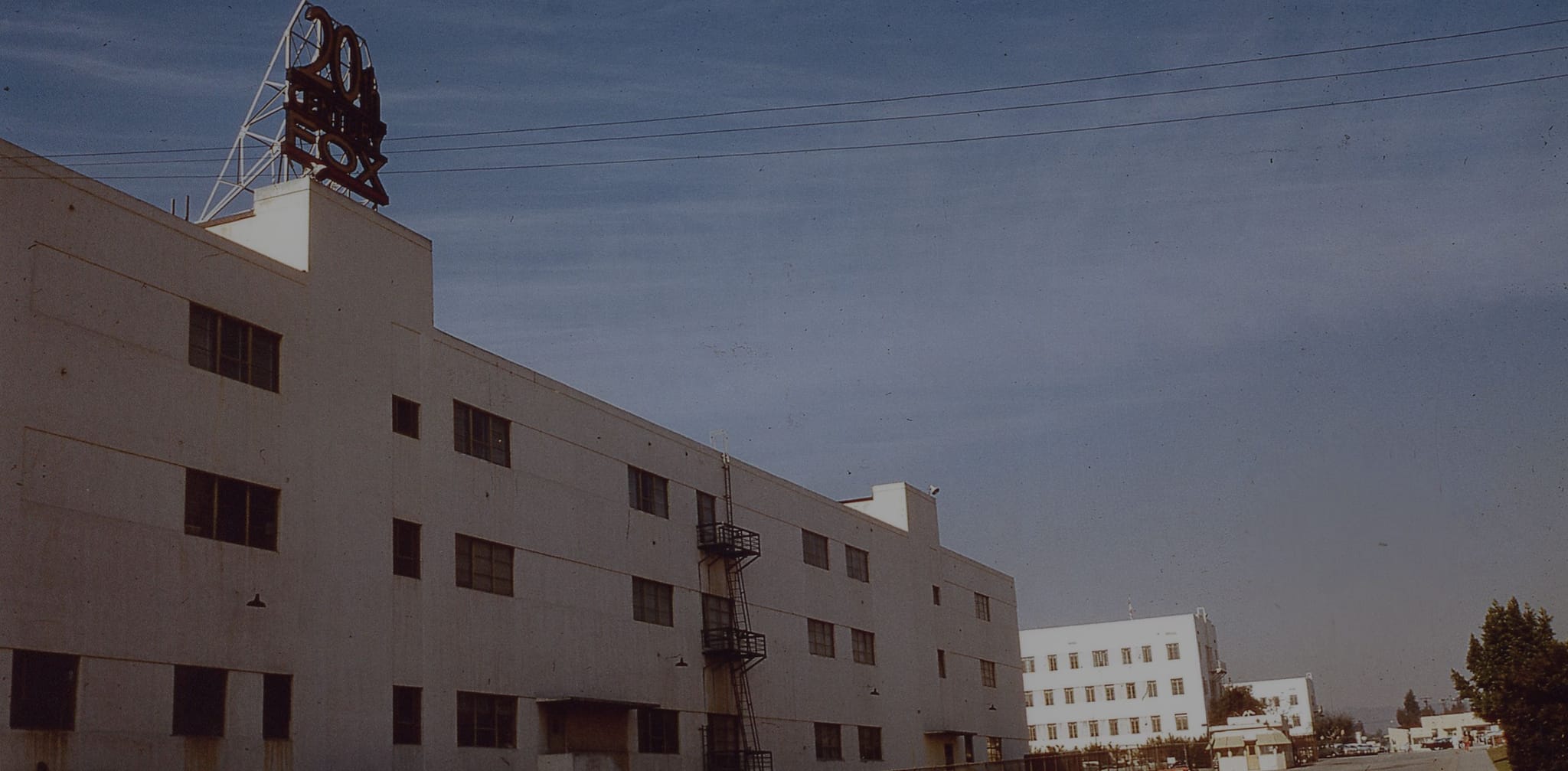 A large white building with a "20th Century Fox" sign on its roof under a blue sky.