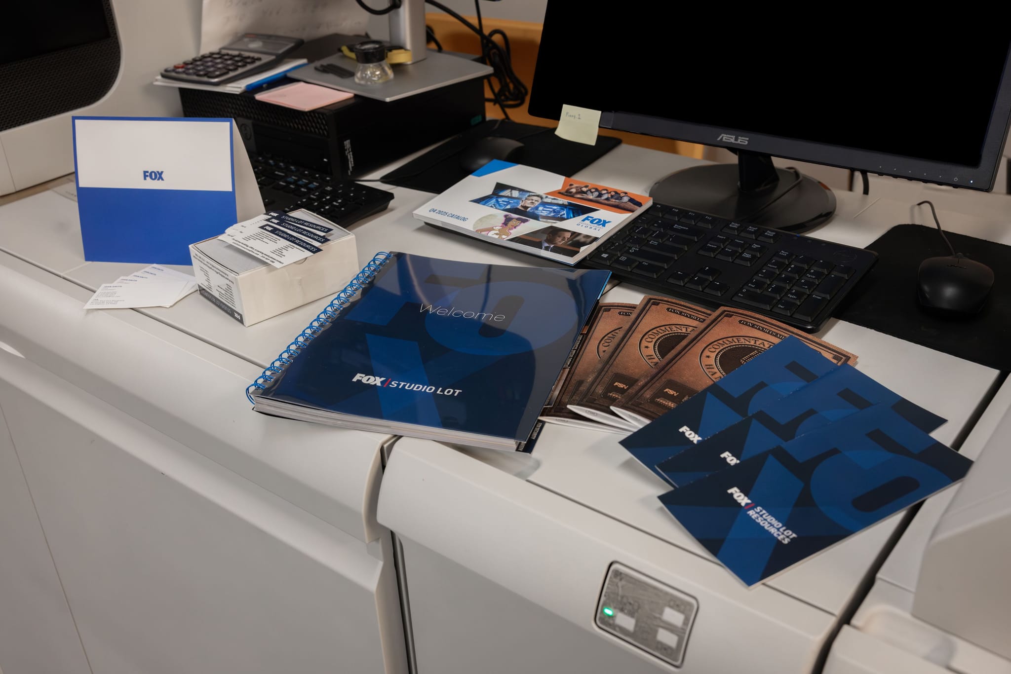 Fox Studio Lot and Studio Services branded booklets, brochures, and a folder on a desk with a computer monitor.