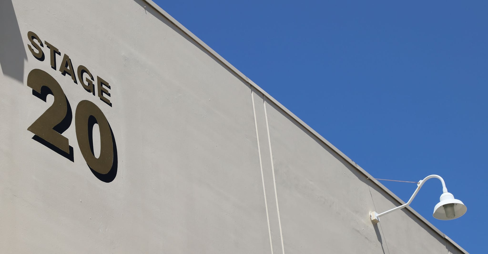 'STAGE 20' on a light-colored building wall under a blue sky.