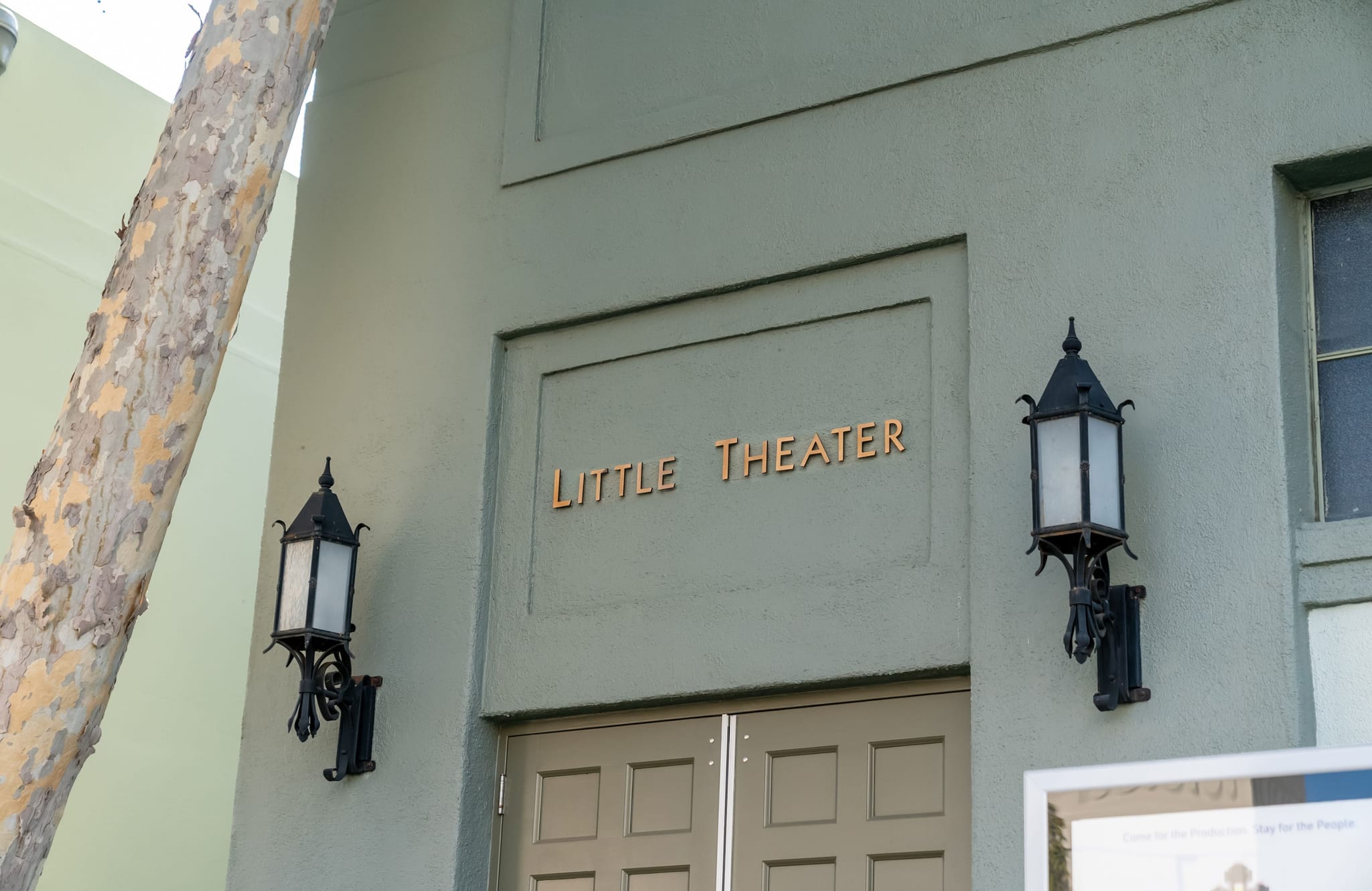 Green building facade with 'LITTLE THEATER' sign above double doors, flanked by two lanterns.