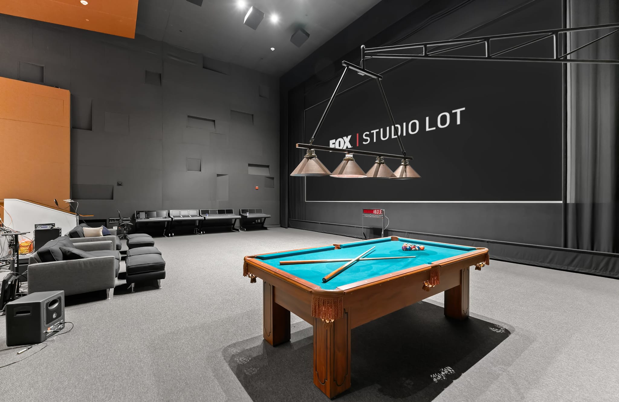 A spacious studio room features a pool table, lounge seating, and a large screen displaying "FOX | STUDIO LOT".
