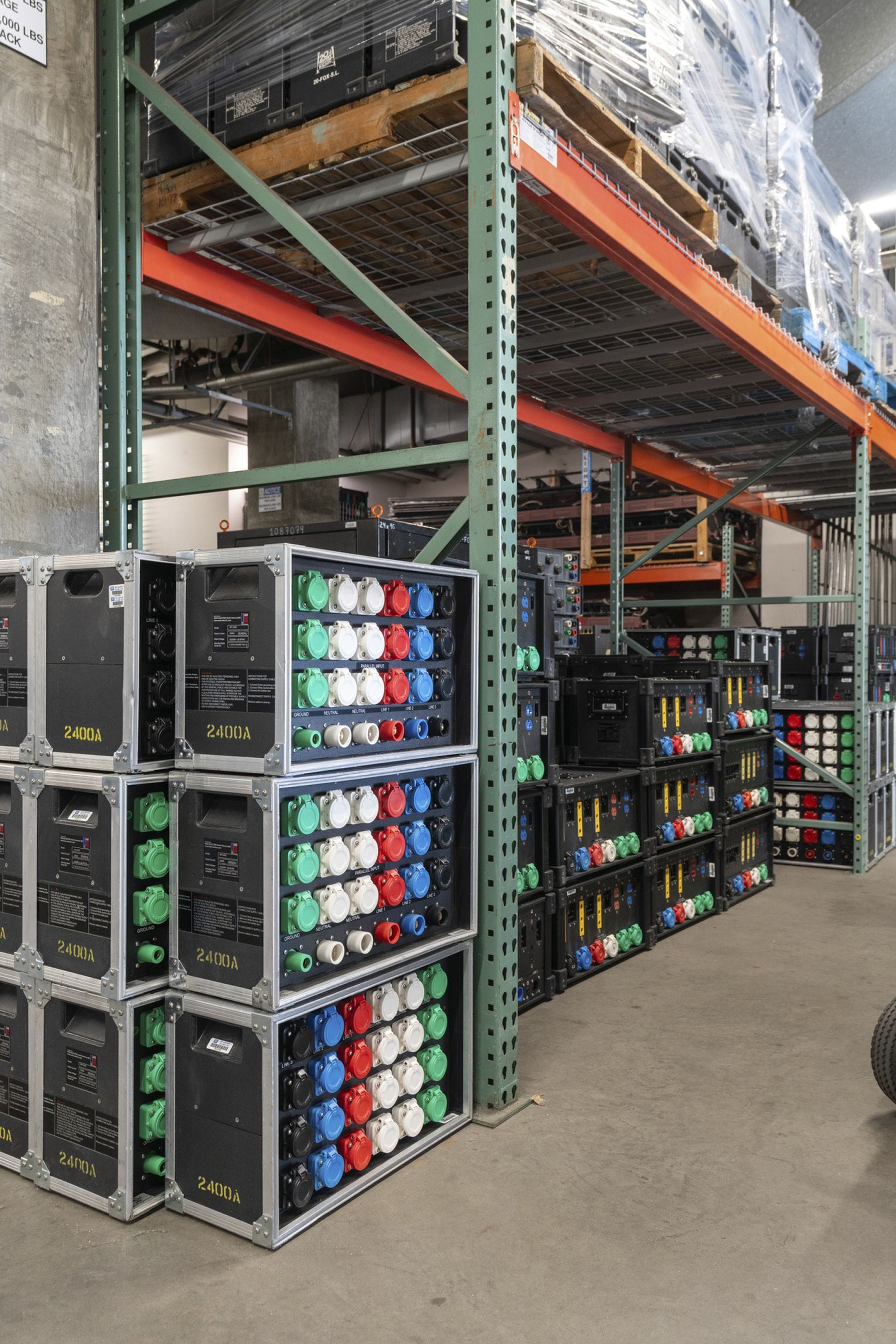 Stacked power distribution units with colorful outlets in a warehouse.
