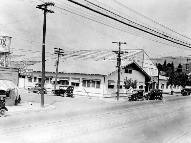 Black and white street scene with vintage cars, "The Studio CAFE," "FOX" water tower, and many utility poles and wires.