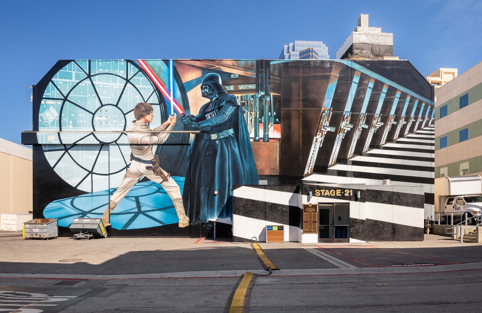 Star Wars mural on a building: Luke Skywalker and Darth Vader duel with lightsabers against a spaceship window and geometric tunnel, with "STAGE 21" above an entrance.