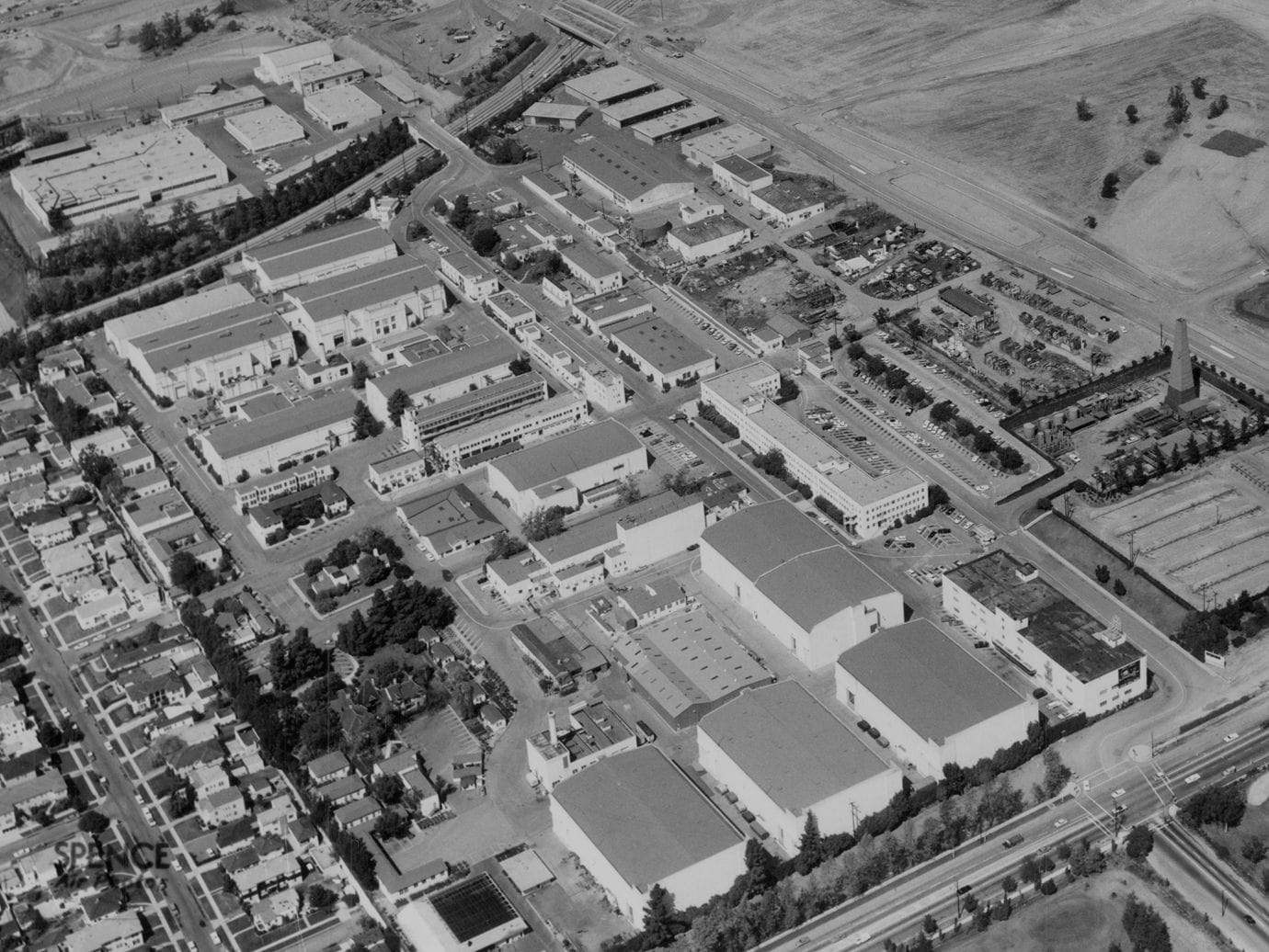 Black and white aerial view of a sprawling film studio complex surrounded by residential neighborhoods and roads.