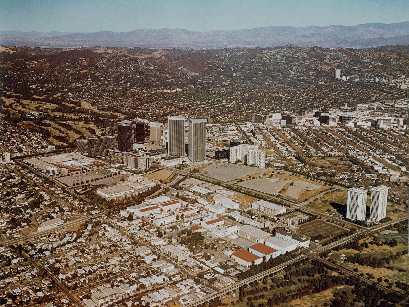 Aerial view of 1970s Century City with the Century Plaza Towers, a golf course, and sprawling residential areas.