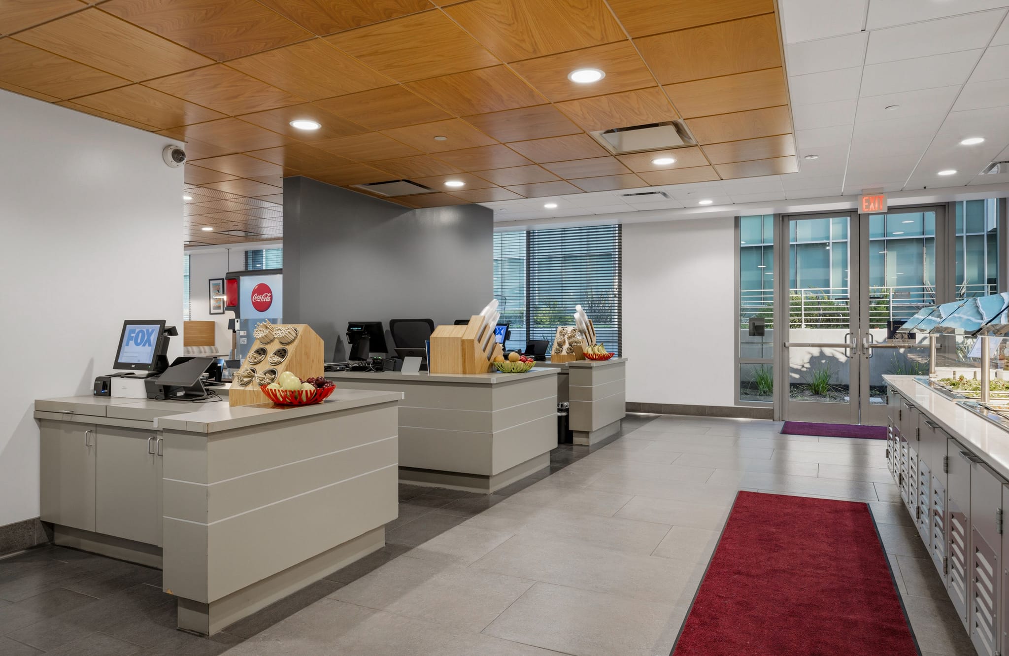 A modern cafeteria with light gray counters, a salad bar, and glass doors.