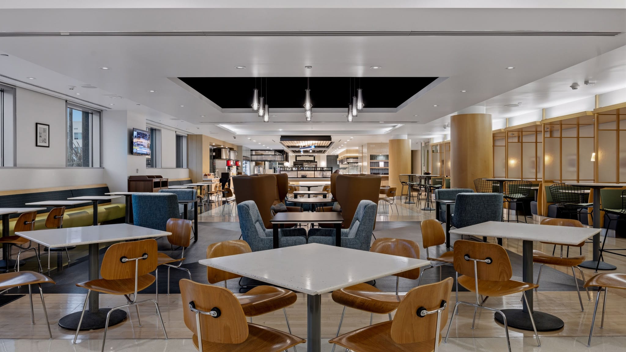 A large, modern cafeteria with diverse seating, including tables, chairs, and booths, in a light and airy space.